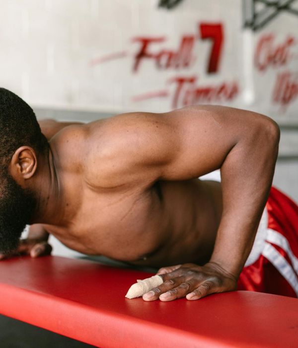 Man performing a controlled bodyweight exercise in a dark, focused environment.
